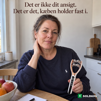 Kvinde ved køkkenbordet med hånden mod kæben holder Kæbero i skødet