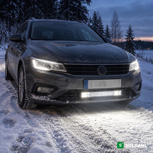 LED-lysbar monteret under kofangeren på en bil på en snedækket vej i skumringen