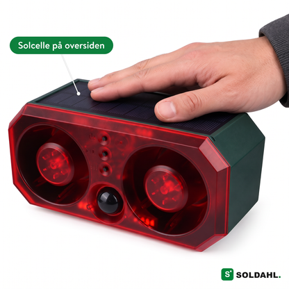 Hånd, der hviler på solcellen øverst på Vildro med to røde hornhøjttalere og sensor