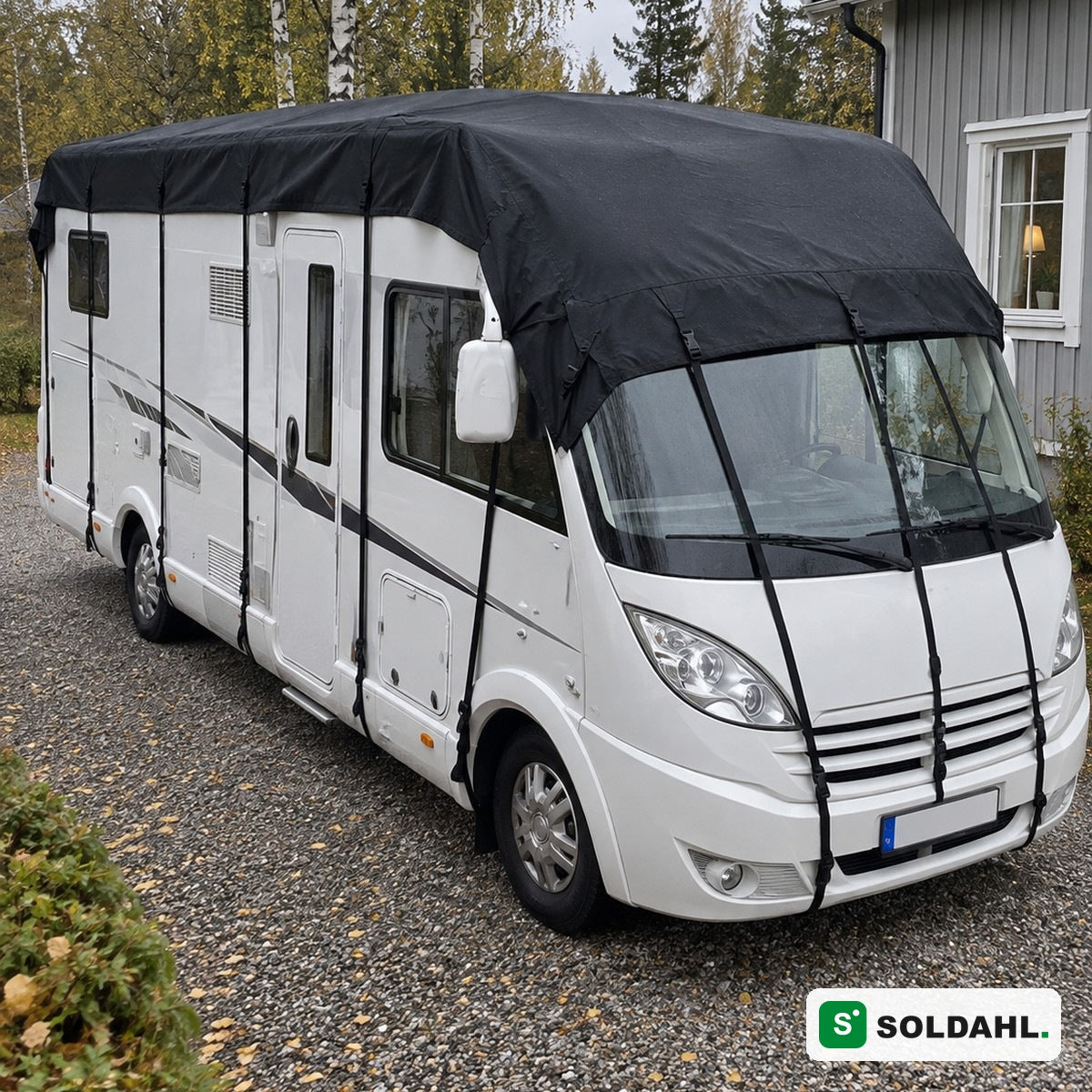 Sort tagbeskyttelse monteret på hvid autocamper på grusindkørsel