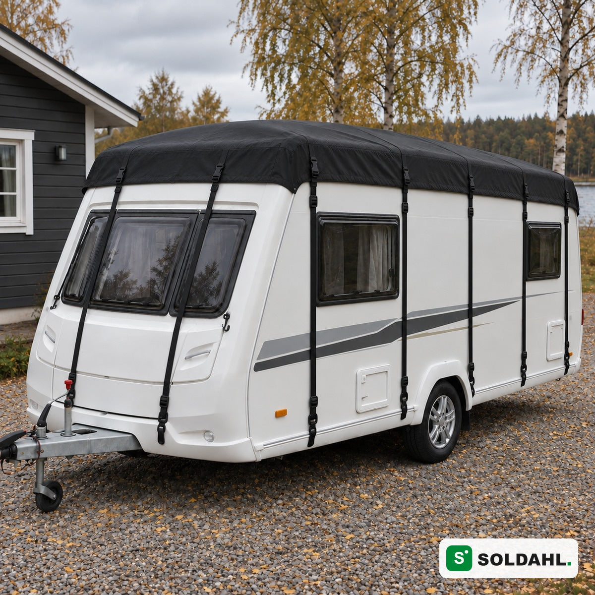 Sort tagbeskyttelse monteret på hvid campingvogn på grusindkørsel